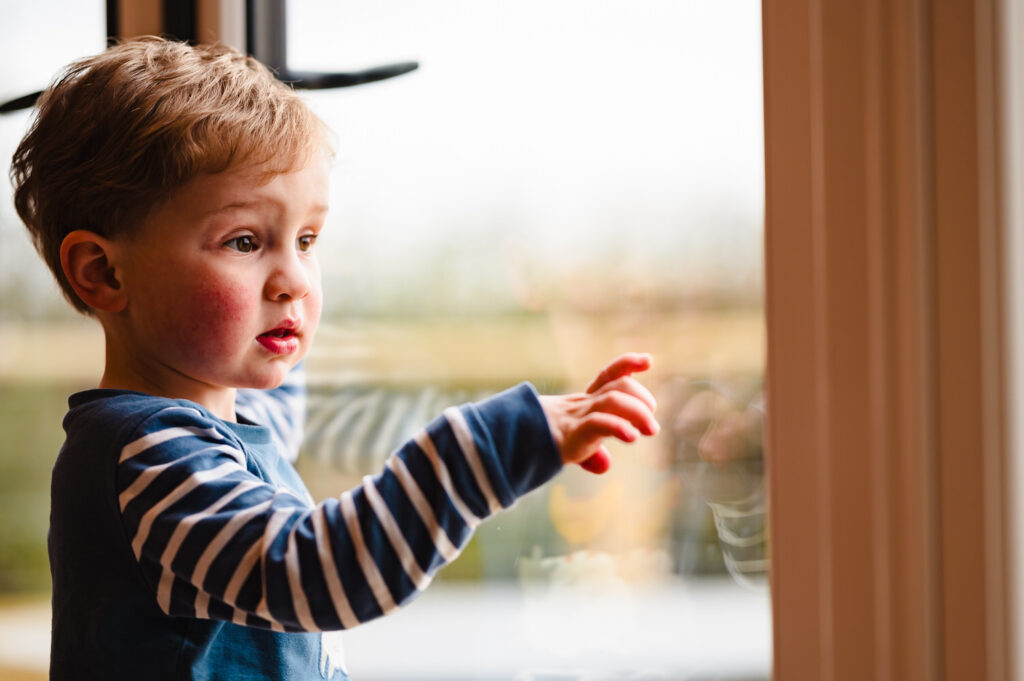 Lifestyle photography of a child looking out at the Rutland countryside from a luxury holiday cabin