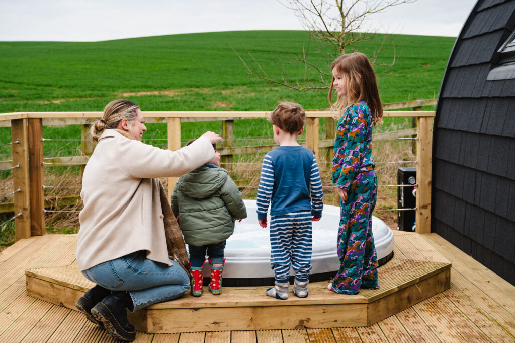 Family lifestyle photography of guests enjoying the outdoor hot tub at a luxury Rutland lodge
