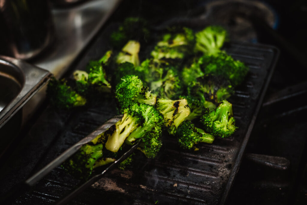 food photography of seared broccoli in a professional kitchen for a hospitality menu.